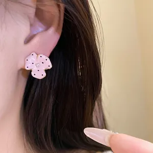Close-up view of elegant pink polka dot flower earring with a central pearl on ear