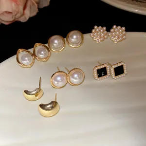 Detailed view of vintage pearl and gold-tone stud earring set displayed on ceramic dish