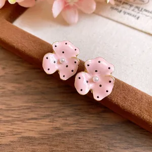Close-up detail of pink enamel polka dot flower stud earrings with center pearl
