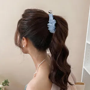 Dettaglio molletta per capelli in chiffon azzurro con sfera d'argento su capelli