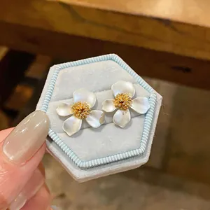 Primo piano di eleganti orecchini a lobo a fiore bianco in una scatola di velluto blu