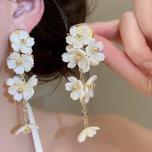 Vue détaillée de longues boucles d'oreilles fleurs blanches et chaînes dorées