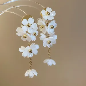 Gros plan de boucles d'oreilles fleurs blanches élégantes avec accents dorés et pétales.