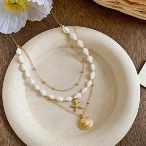 Vue détaillée du collier doré multicouche avec des perles de coquillage et des pendentifs.