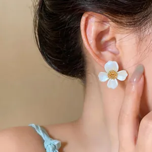 Dettaglio ravvicinato di eleganti orecchini a lobo a fiore bianco indossati da una modella
