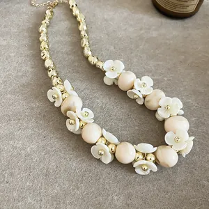 Collier élégant avec fleurs blanches et perles dorées, parfait pour un look d'été doux.