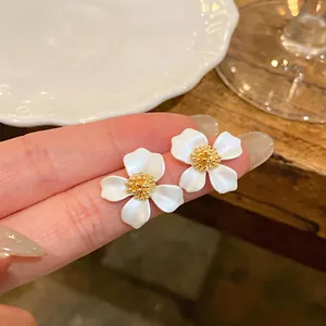 Dettaglio macro di eleganti orecchini a lobo a forma di fiore in smalto bianco e oro