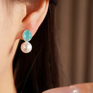 Close-up of elegant silver stud earring featuring a blue oval gem and white pearl
