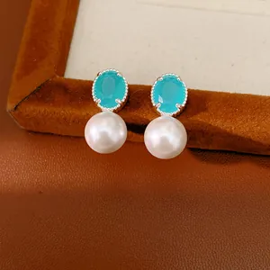 Detailed view of elegant turquoise oval zircon and white pearl drop earrings.