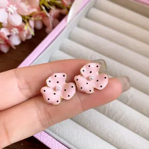 Detailed close-up of elegant pink polka dot flower stud earrings with a tiny pearl center