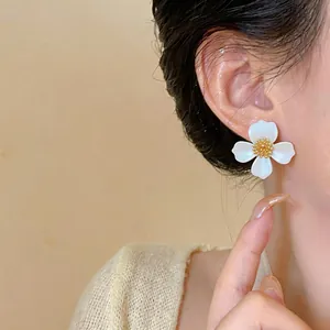 Dettaglio macro di elegante orecchino a perno a fiore bianco con stame dorato