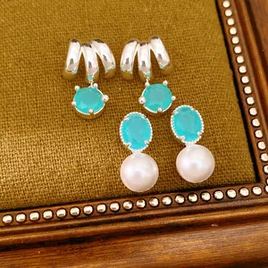 Close-up detail of silver stud earrings with turquoise stones and elegant white pearls