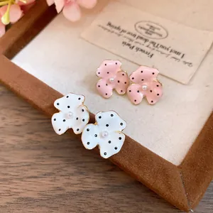 Close-up detail of polka dot flower earrings with pearl center and enamel finish