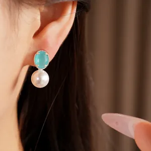Detail shot of an elegant earring featuring a turquoise stone and a round lustrous pearl.