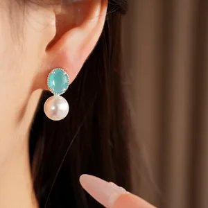 Close-up of elegant silver stud earrings featuring turquoise zircon and round white pearl