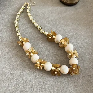 Gros plan d'un collier de fleurs élégant avec des perles crème et des pétales d'ambre.