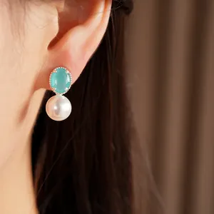 Detailed view of elegant pearl stud earrings featuring a turquoise gemstone on ear