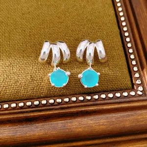 Close-up detail of elegant geometric silver-tone earrings with round sea-blue gemstones