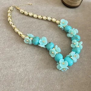 Gros plan d'un collier de fleurs d'été avec des perles turquoise et finition dorée