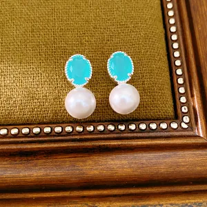 Close-up of elegant silver needle pearl earrings with turquoise stones on vintage background