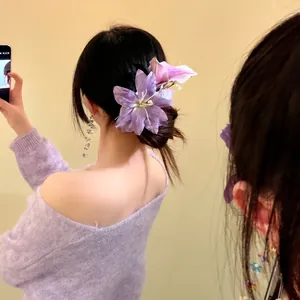 Detailed view of an elegant oversized purple lily fabric flower hair clip worn on a bun.