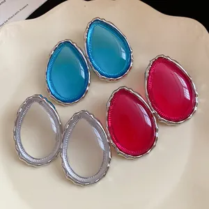 Macro detail of colorful water drop resin earrings with silver borders on a decorative plate