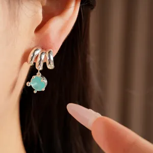 Detailed view of elegant silver-tone stud earring with light blue stone on an Asian model's ear