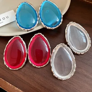 Close-up of vintage resin teardrop stud earrings in blue, red, and clear colors