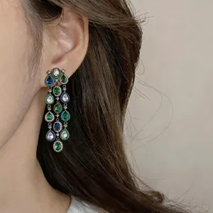 Detaillierte Makroansicht eleganter langer Quastenohrringe mit blauem und grünem Zirkon