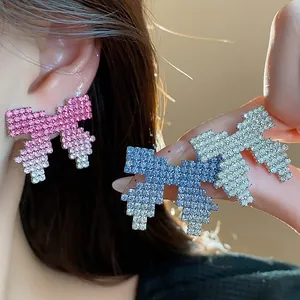 Close-up of pixel art bow earrings featuring sparkling gradient rhinestones.