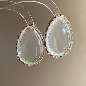 Close-up of elegant clear resin teardrop earrings with silver-toned metallic frame