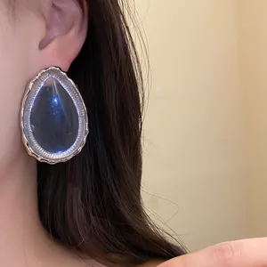 Close-up detail of vintage resin waterdrop earrings with silver frames worn by a model