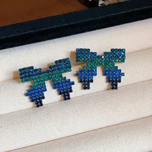 Close-up of pixelated bow earrings with blue and green gradient pavé crystals