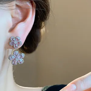 Close-up of elegant pink flower zircon earrings with silver needles on a model ear
