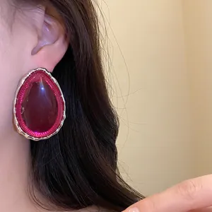 Detail view of vintage magenta resin teardrop stud earring with gold-tone metallic border