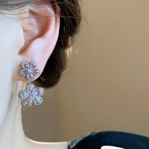 Close-up detail view of delicate pink zircon flower stud earrings worn on a model's ear