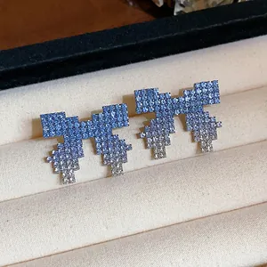 Close-up of elegant blue gradient crystal bow stud earrings on a velvet display