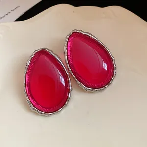 Detailed view of vibrant pink resin teardrop stud earrings with textured silver edge.