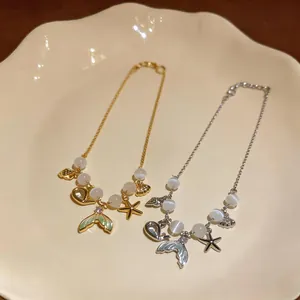 Detail view of gold and silver mermaid tail and starfish charm bracelets with cat-eye stones
