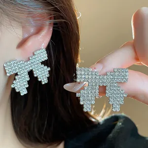 Macro view of exquisite silver needle rhinestone bow stud earrings with sparkling crystals.