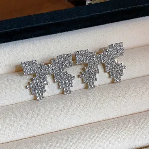 Close-up of pixelated bow stud earrings with sparkling rhinestones in a velvet box.