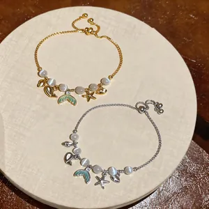 Close-up of elegant starfish and fish tail charm bracelets with cat's eye stones in gold and silver