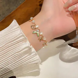 Close-up of elegant beaded bracelet with starfish and mermaid tail charms worn on wrist