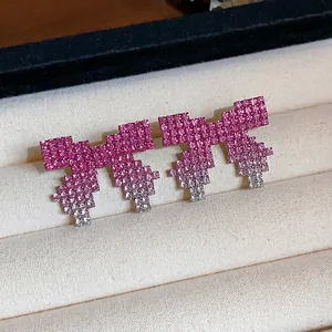 Close-up of pixelated bow earrings with pink gradient rhinestones in a luxury jewelry box