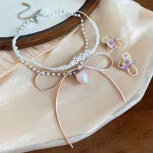 Detailed view of the strawberry pendant and lace texture on the pearl necklace set