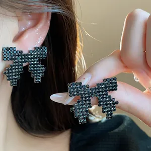Detailed macro view of pixelated black bowknot stud earrings with black crystals