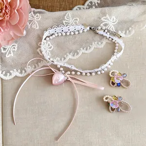 Detail view of sweet lace choker with pink heart pendant and floral stud earrings