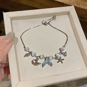 Close-up view of a delicate sea star and fish tail cat eye stone beaded bracelet in box