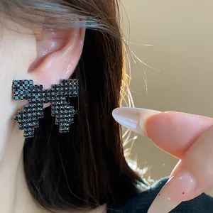 Detailed close-up showing black rhinestone pixel bow earrings with elegant sparkling finish