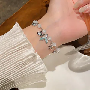 Close-up of a delicate mermaid tail and starfish charm bracelet with cat's eye stones.